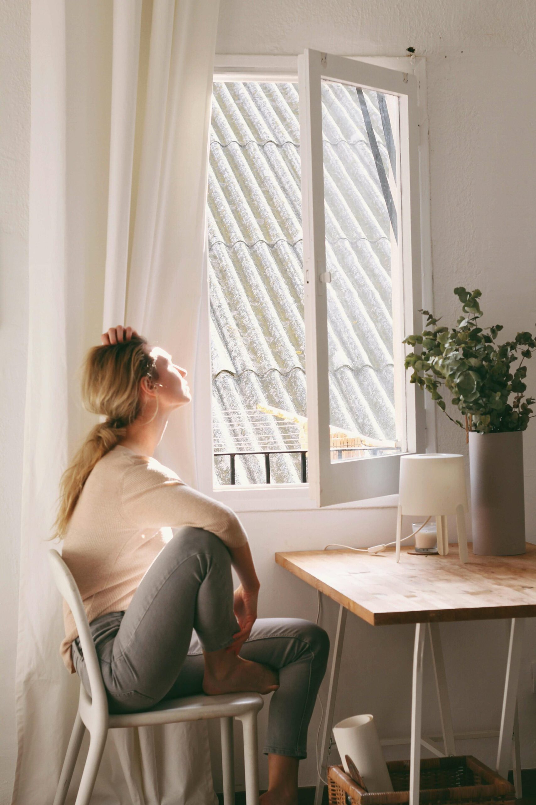 femme profitant du soleil assise à la fenêtre